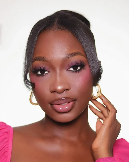 Black woman with make up. Bright Pink Blush appled underneath the eyes and on the apples of the cheek to emulate a baby doll look